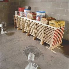 a fan sitting on top of a wooden pallet next to a wall mounted heater