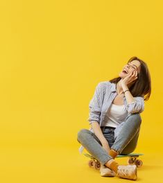 a young woman sitting on top of a skateboard with her mouth open and eyes closed