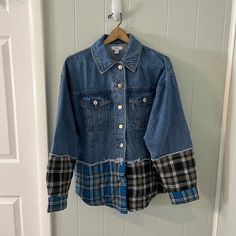 a blue jean jacket hanging on a white door with a black checkered shirt underneath it