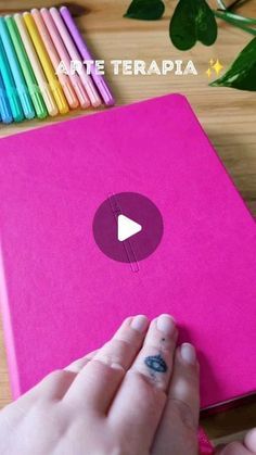 a person holding a pink notebook with colored pencils on it and the text, ate terapia