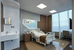 a hospital room with a bed, sink and mirror