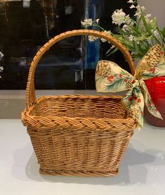 a wicker basket sitting on top of a counter next to a vase with flowers in it