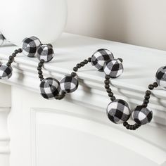 a black and white checkered beaded necklace is hanging on the wall next to a vase