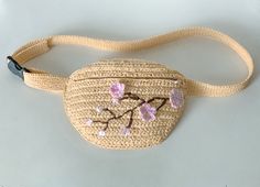 a crocheted purse with pink flowers on the side and a small black hook