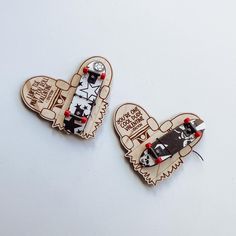 two wooden brooches depicting skateboarders on white background