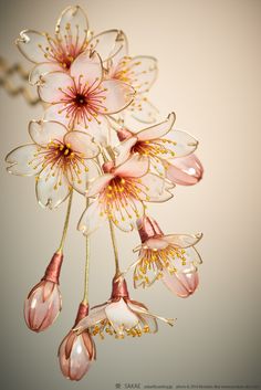 some pink and white flowers hanging from a ceiling fixture with water droplets on it's petals