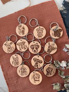 six wooden keychains with dogs engraved on them sitting on a piece of cloth