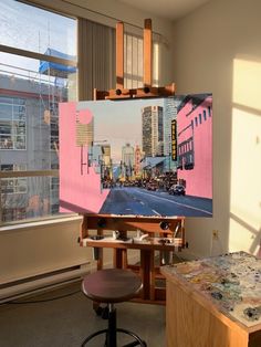 an artist's easel in front of a window with cityscape painted on it