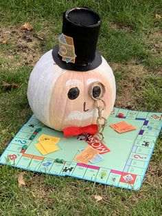 a game board with a pumpkin wearing a top hat on it's head, sitting in the grass