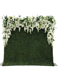 an artificial grass wall with white flowers and greenery on top, in front of a white background