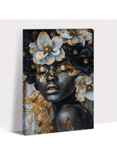 an abstract painting with gold and black flowers on the face, in front of a white wall