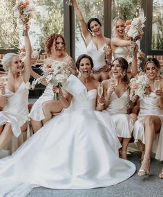 a group of bridesmaids pose for a photo with champagne flutes in their hands