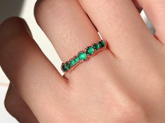 a woman's hand with a green ring on top of her finger and an emerald stone in the middle