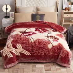 a red and white comforter set with flowers on it in the middle of a room