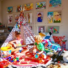 two young children sitting on a bed playing guitar in front of a teepee tent