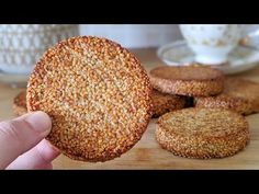 someone is holding up some cookies on a cutting board with other food items in the background