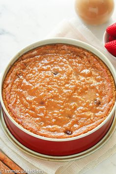 a cake in a red pan sitting on top of a table next to some strawberries