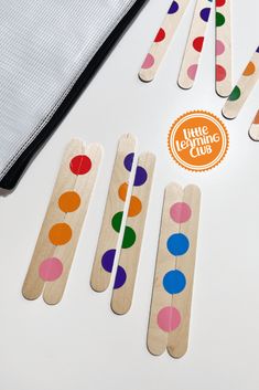 four wooden pegs with different colored dots on them next to a piece of fabric