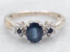 an oval shaped sapphire and diamond ring with three smaller diamonds around the band on a white background