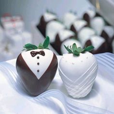 two chocolate covered strawberries are sitting on a table with other desserts in the background