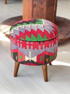 a colorful ottoman sitting on top of a hard wood floor next to a wooden table