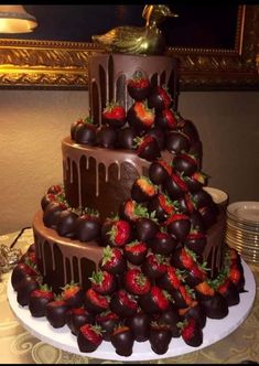 a triple layer chocolate cake with strawberries on the top and bottom, sitting on a table