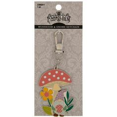 a key chain with a mushroom and flowers on it's front, in the packaging