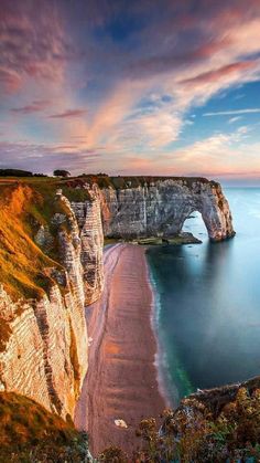 an image of the coast and cliffs at sunset with pink clouds in the sky above