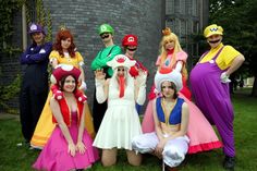 a group of people dressed up in costumes posing for a photo on the grass near a brick building