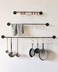 pots and pans are hanging on the wall next to utensils in hooks