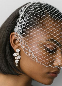 a woman wearing a veil with flowers on her head and earring in front of her face