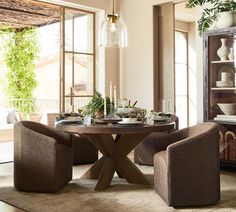 a dining room table with chairs around it in front of large windows and open shelves