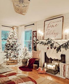 a living room decorated for christmas with stockings on the mantel and trees in pots