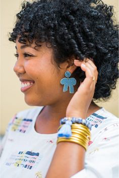 Our Berkeley Bow earring in cornflower blue is a chic statement that adds a bit of a classic look to any outfit! This earring features the perfect shade of blue beads outlined by a fine gold thread. This earring is lightweight, hypoallergenic, and measures 2" L x 1.5" W. Each earring features soft, acrylic felt backing. Due to the handmade nature of our beaded styles, each may vary. This listing is for one pair of earrings. Light Blue Beaded Drop Earrings, Bow Earring, Shade Of Blue, Gold Thread, Bow Earrings, Gold Threads, Cornflower Blue, Blue Beads, Shades Of Blue