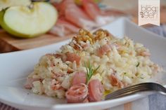 a white plate topped with rice covered in ham and vegetables next to an apple slice