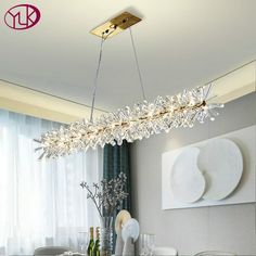 a modern chandelier hanging over a dining room table with chairs and vases