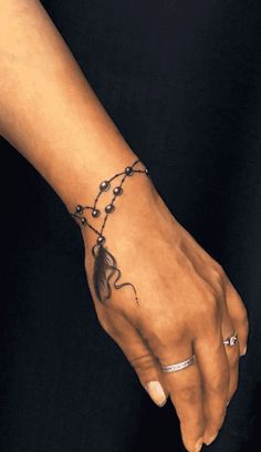 a woman's hand with a tattoo on it and a chain around the wrist