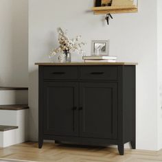 a black cabinet sitting on top of a hard wood floor next to a stair case