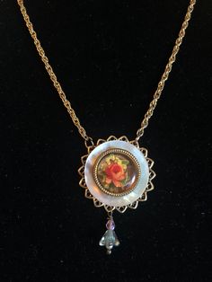 These lovely garden roses rest on a Mother of Pearl button all mounted on a filigree background.  The 18 " golden Singapore chain has a decorative heart toggle clasp. Vintage Rose Gold Filigree Necklace, Vintage Rose Gold Filigree Necklaces, Vintage Necklace With Flower Charm Round Pendant, Vintage Necklace With Round Pendant And Flower Charm, Vintage Necklaces With Flower Charm Round Pendant, Antique Gold Jewelry With Rose Design, Vintage Rose Design Pendant Jewelry, Vintage Rose Design Necklaces In Rose Color, Rose-colored Rose Design Round Necklaces