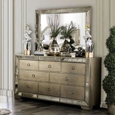 a large mirror sitting on top of a dresser next to a vase filled with flowers