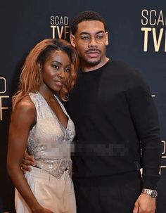 a man standing next to a woman on a red carpet