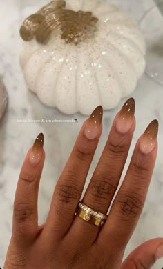 a woman's hand with two gold rings on it and a white pumpkin in the background