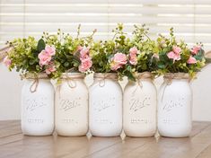 four mason jars with flowers in them sitting on a table