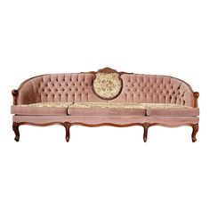 an old fashioned pink couch with ornate carvings on the armrests and back, against a white background