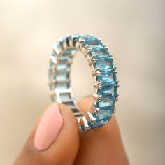 a woman's hand holding a ring made out of blue topazte stones