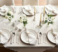 the table is set with white flowers and silverware