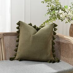 a green pillow sitting on top of a wicker chair next to a vase with flowers