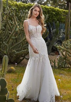 a woman standing in front of cactus bushes wearing a wedding dress