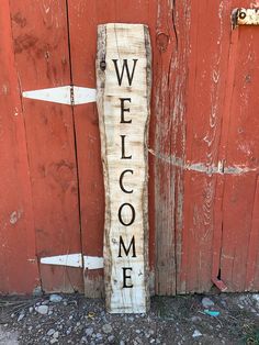 a wooden welcome sign sitting next to a red barn