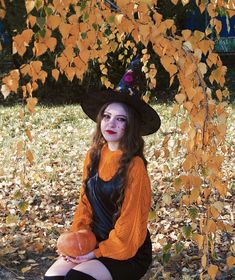 a woman dressed as a witch sitting under a tree